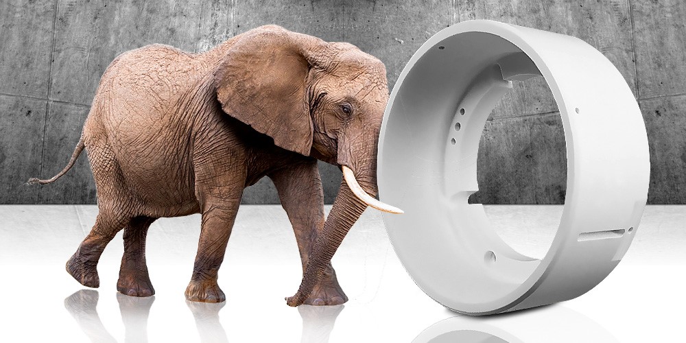 Elefantti työntää kärsällään PET muovista valmistettua vaaleaa muoviosaa