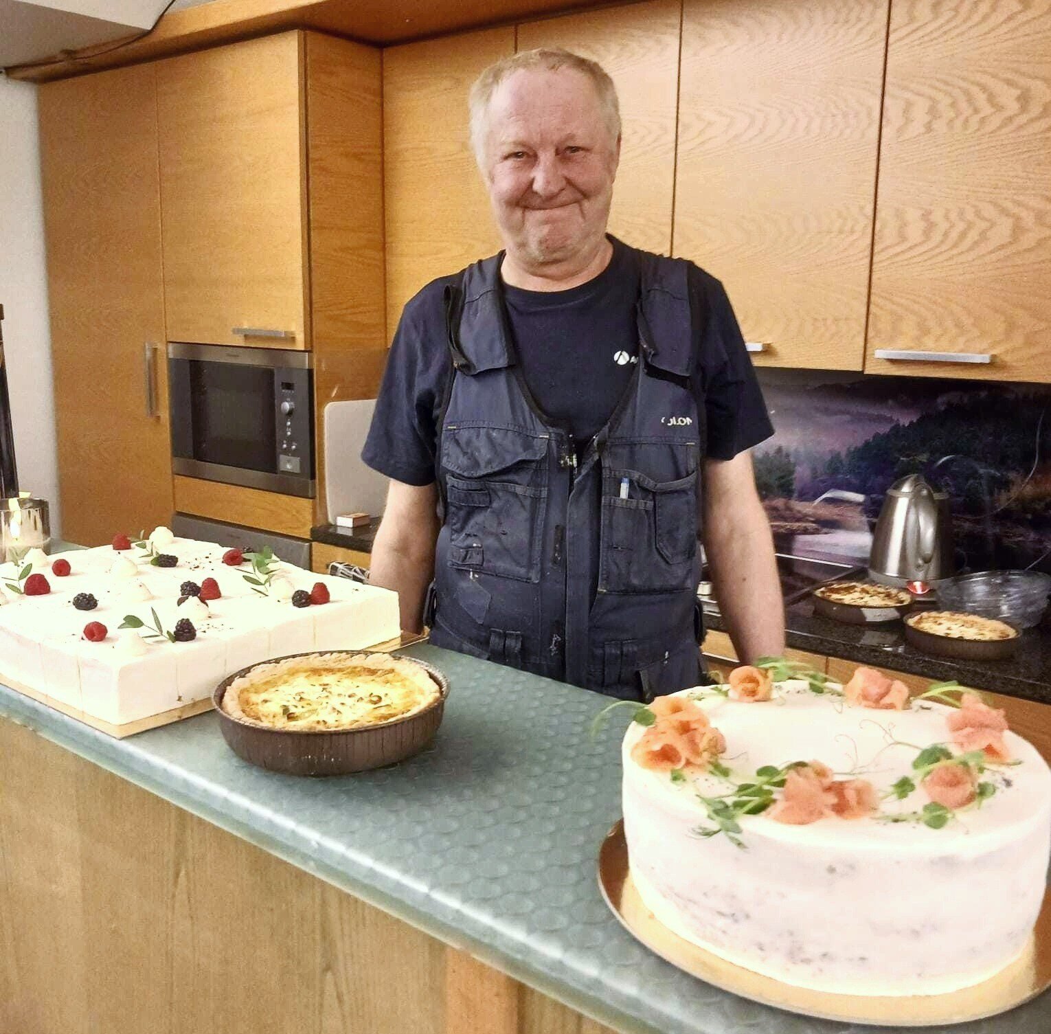 Arppa seisoo pöydän takana jonka edessä on suolaista ja makeaa kakkua sekä piirakka juhlistamassa eläkkeelle jäämistä. 